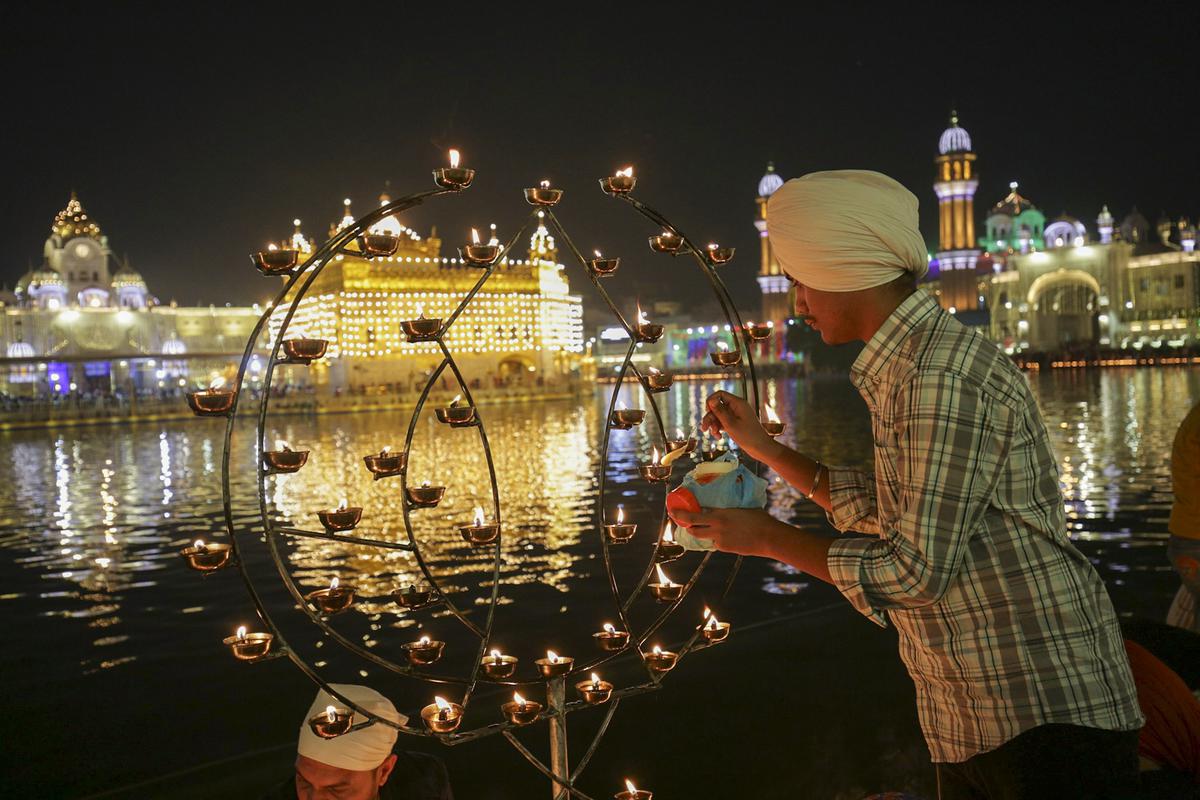 Devotees light lamps at the Golden Temple on Diwali festival, in Amritsar, Sunday, Nov. 12, 2023. 